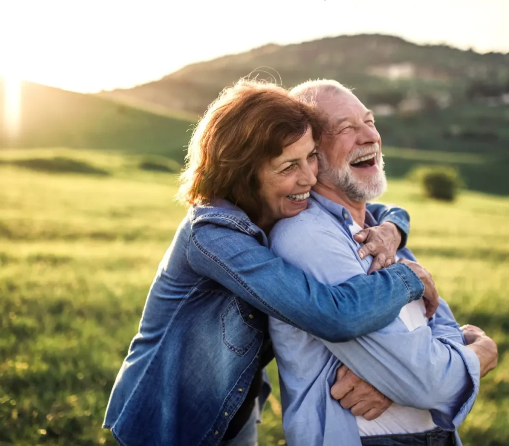 Side view of senior couple hugging outside in spring nature at sunset