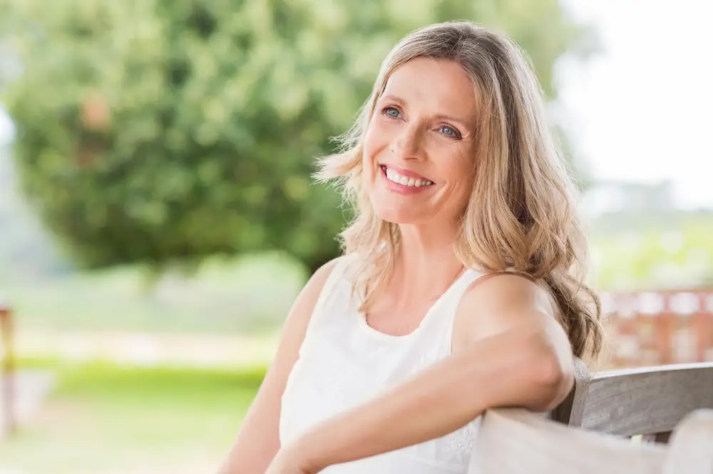 blonde woman smiling and seeing clearly into the distance outside